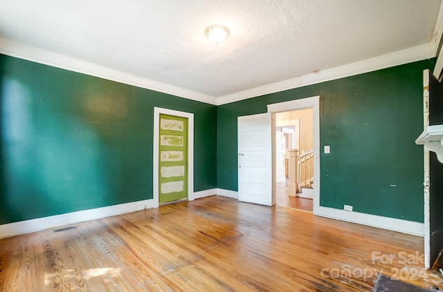 empty room with light hardwood / wood-style floors, a textured ceiling, and ornamental molding