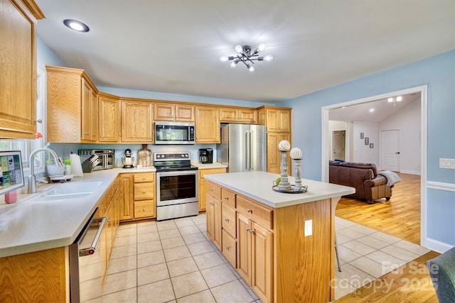 kitchen featuring stainless steel appliances, a center island, sink, and light tile patterned floors