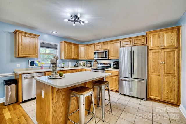 kitchen featuring light tile patterned floors, a kitchen breakfast bar, a center island, and appliances with stainless steel finishes