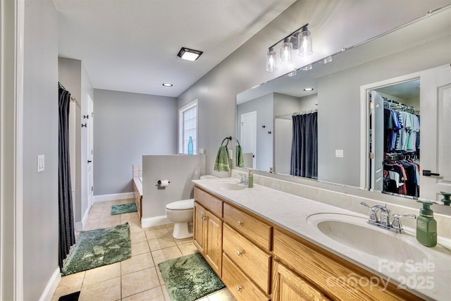 bathroom featuring tile patterned floors, a tub to relax in, toilet, and vanity