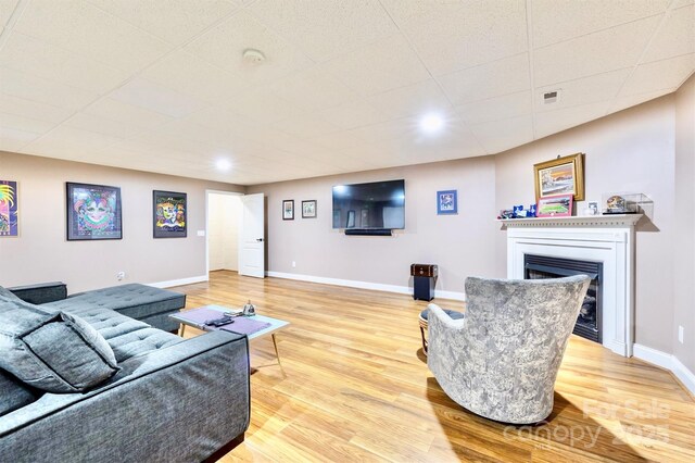 living room featuring a drop ceiling and light hardwood / wood-style flooring