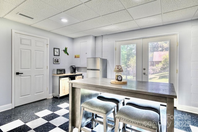 kitchen featuring stainless steel refrigerator, wood counters, a kitchen bar, a drop ceiling, and french doors