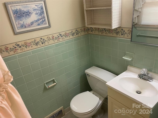 bathroom with toilet, tile walls, and vanity