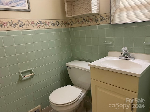 bathroom featuring tile walls, toilet, and vanity