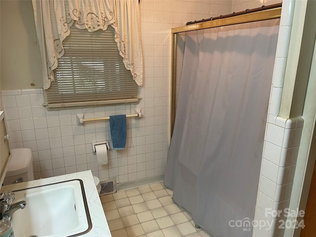 bathroom with toilet, tile walls, tile patterned floors, walk in shower, and sink