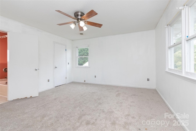 unfurnished bedroom with light carpet, ensuite bath, multiple windows, and ceiling fan