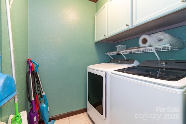 laundry area featuring separate washer and dryer, light tile patterned floors, and cabinets