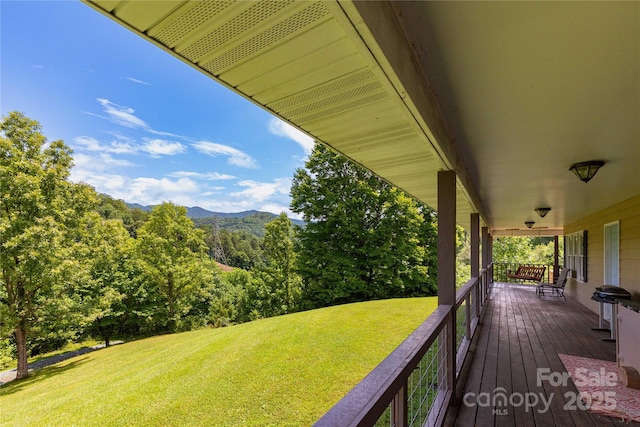 deck featuring a mountain view, a lawn, and a porch