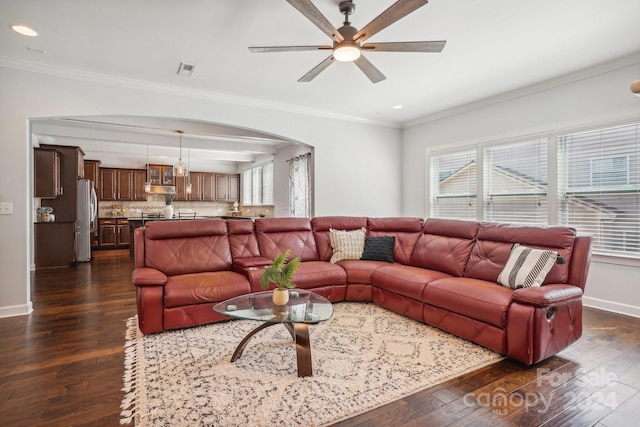 living room featuring ceiling fan, dark wood-type flooring, crown molding, and a healthy amount of sunlight