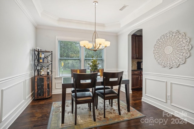 dining area featuring a raised ceiling, dark hardwood / wood-style flooring, crown molding, and a chandelier