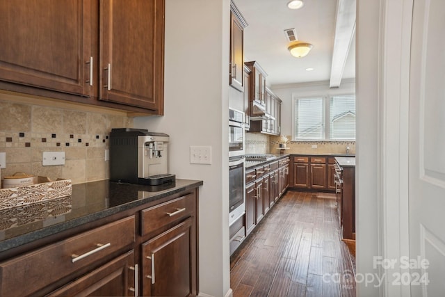 kitchen with backsplash, dark hardwood / wood-style floors, stainless steel gas stovetop, and dark stone counters