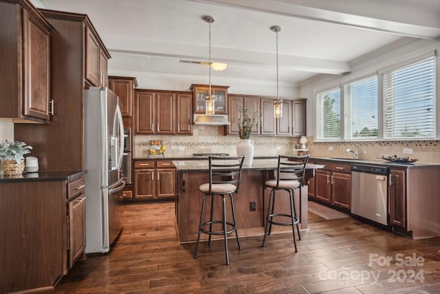 kitchen with stainless steel appliances, dark hardwood / wood-style floors, decorative light fixtures, dark stone countertops, and a center island