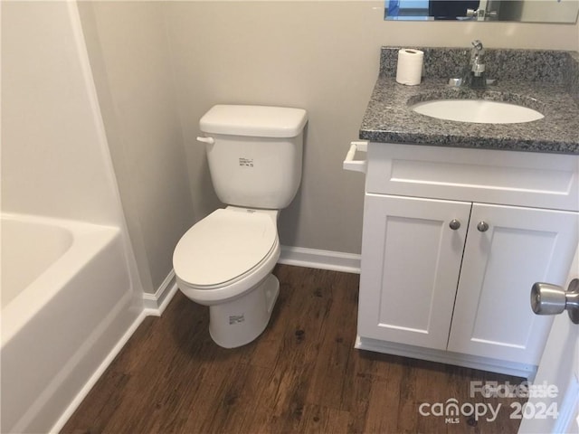 bathroom with a washtub, wood-type flooring, vanity, and toilet