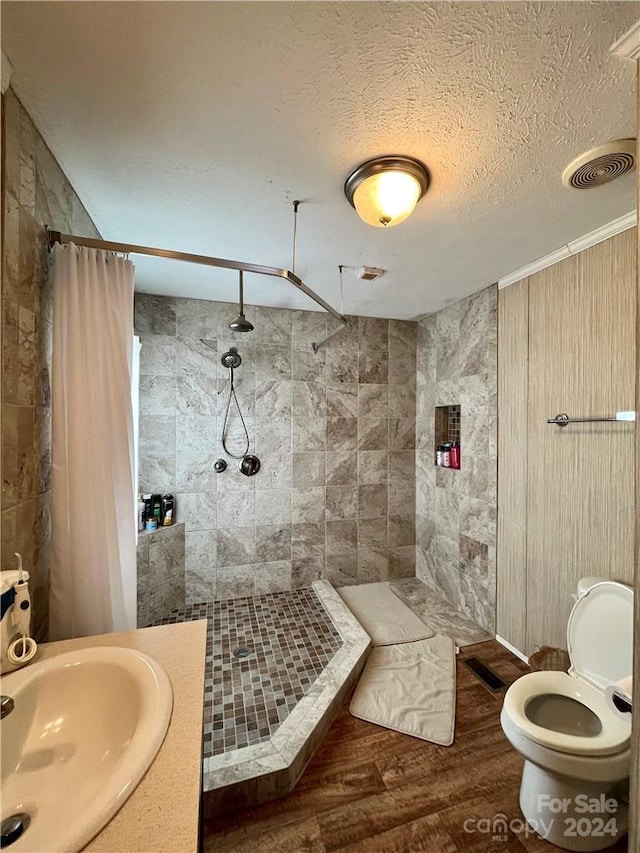 bathroom featuring toilet, hardwood / wood-style flooring, sink, a textured ceiling, and curtained shower