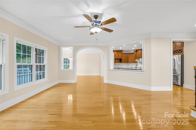 unfurnished living room featuring ceiling fan, light wood-type flooring, and crown molding