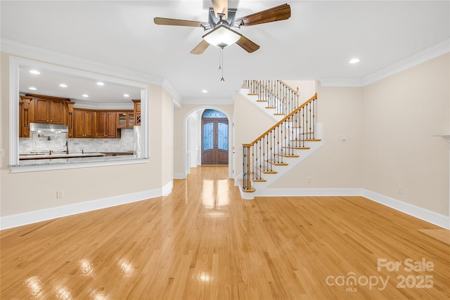 unfurnished living room with ceiling fan, crown molding, light hardwood / wood-style floors, and french doors