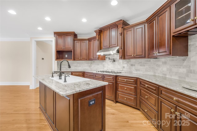 kitchen featuring a kitchen island with sink, sink, crown molding, and decorative backsplash