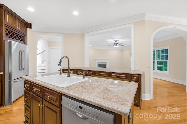 kitchen with ceiling fan, sink, crown molding, a kitchen island with sink, and appliances with stainless steel finishes