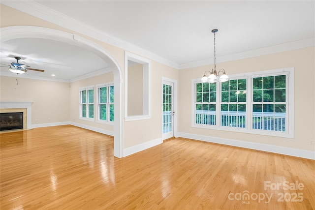 unfurnished living room with ceiling fan with notable chandelier, light hardwood / wood-style flooring, ornamental molding, and a premium fireplace