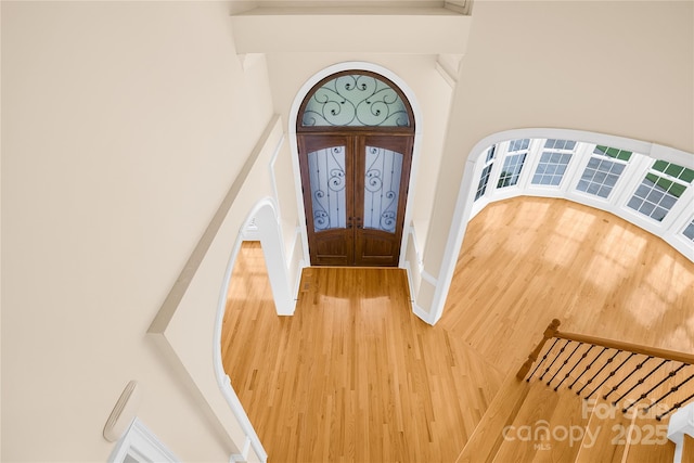 entrance foyer with hardwood / wood-style floors, a towering ceiling, and french doors