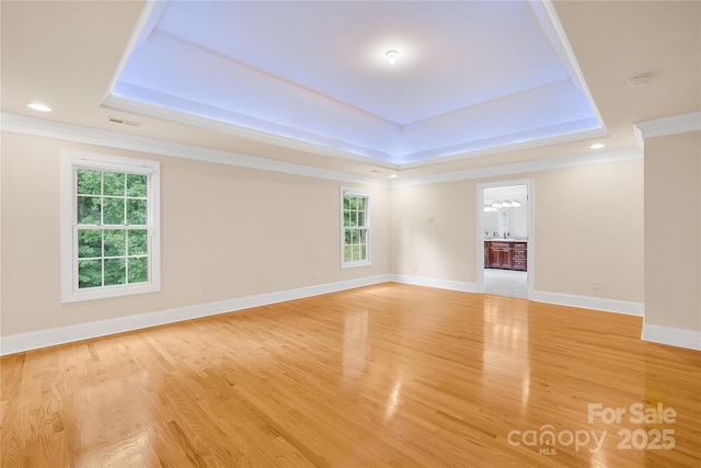 unfurnished room with light hardwood / wood-style floors, a tray ceiling, and ornamental molding