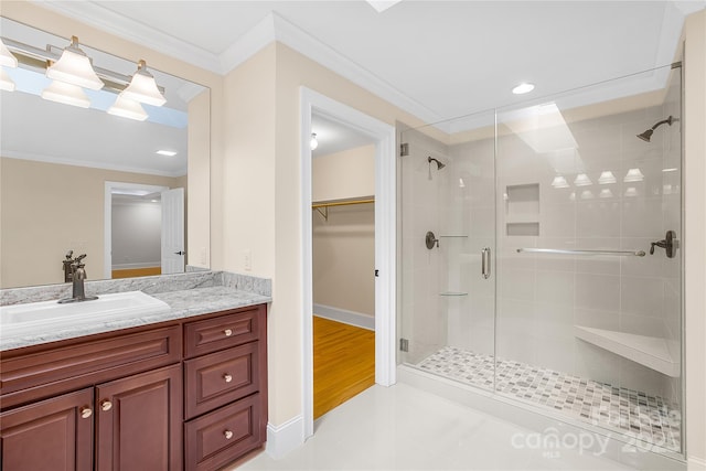 bathroom featuring a shower with shower door, vanity, crown molding, and tile patterned flooring