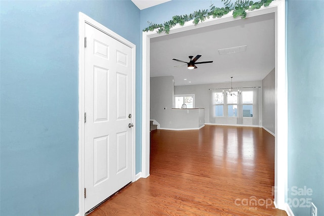 spare room with ceiling fan with notable chandelier and light wood-type flooring