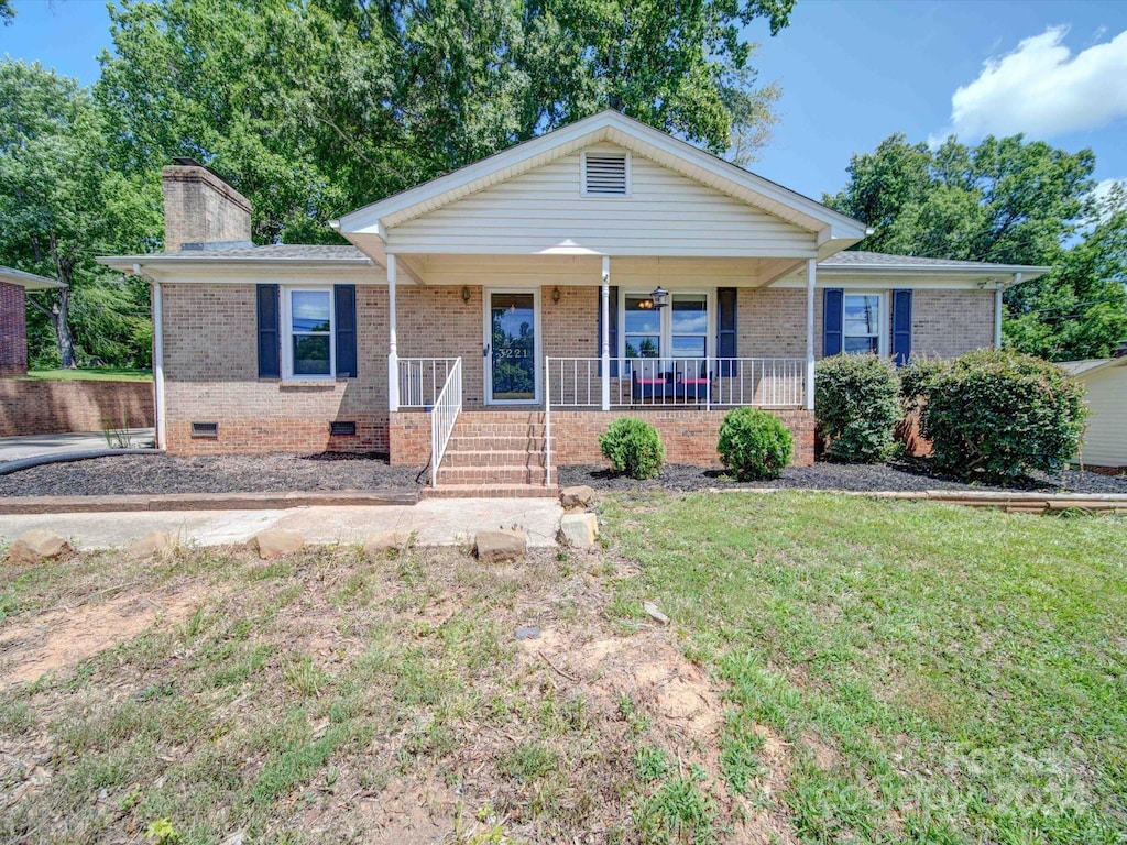 ranch-style house with a porch and a front lawn