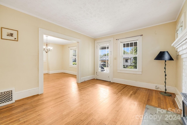 interior space with a textured ceiling, a notable chandelier, and light wood-type flooring