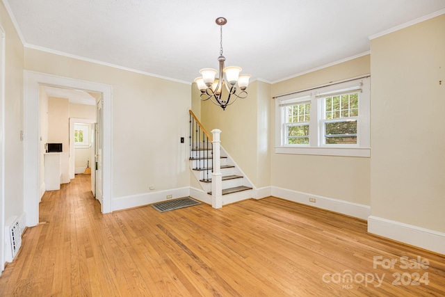 empty room with crown molding, a chandelier, and light hardwood / wood-style flooring