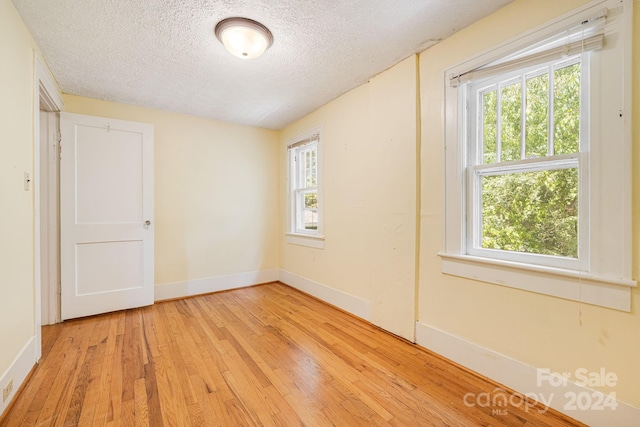 empty room featuring a textured ceiling and light hardwood / wood-style flooring