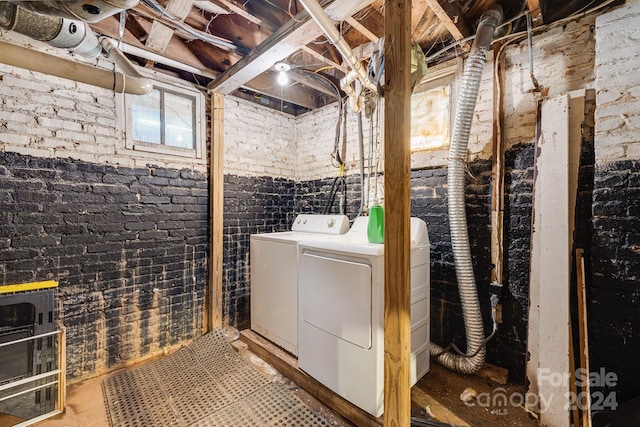 washroom featuring washing machine and dryer and brick wall