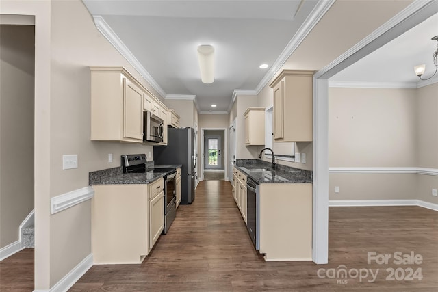 kitchen with stainless steel appliances, hardwood / wood-style floors, ornamental molding, sink, and dark stone countertops