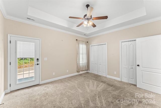 unfurnished bedroom featuring ceiling fan, a raised ceiling, and multiple windows