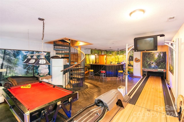 recreation room with bar, a bowling alley, and a textured ceiling