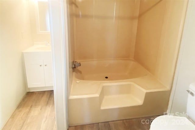 full bathroom with toilet, vanity, wood-type flooring, and washtub / shower combination