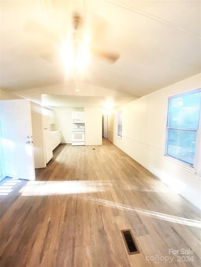 additional living space with light hardwood / wood-style floors and lofted ceiling