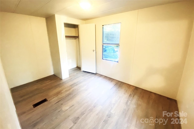 unfurnished bedroom featuring hardwood / wood-style floors and a closet