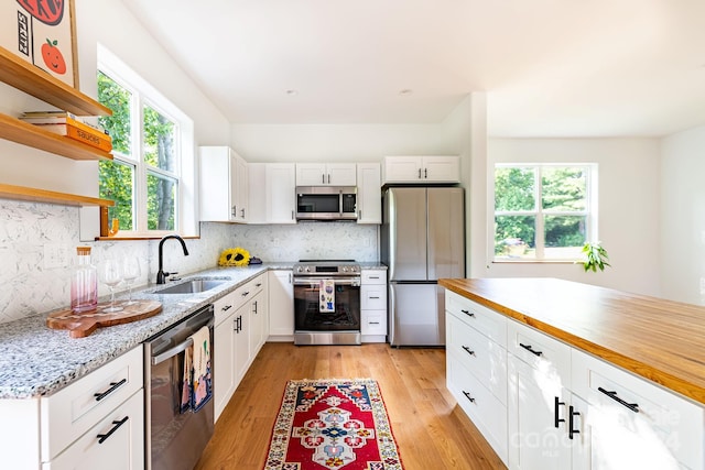 kitchen featuring sink, appliances with stainless steel finishes, white cabinets, and light hardwood / wood-style floors