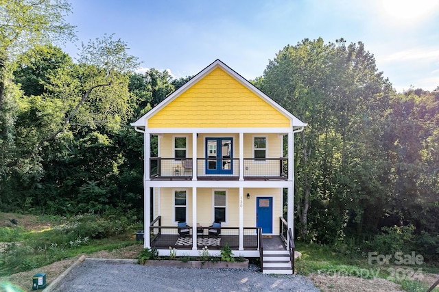 view of front of house featuring covered porch, a balcony, and french doors