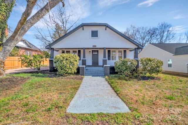 bungalow with fence, a porch, and a front yard