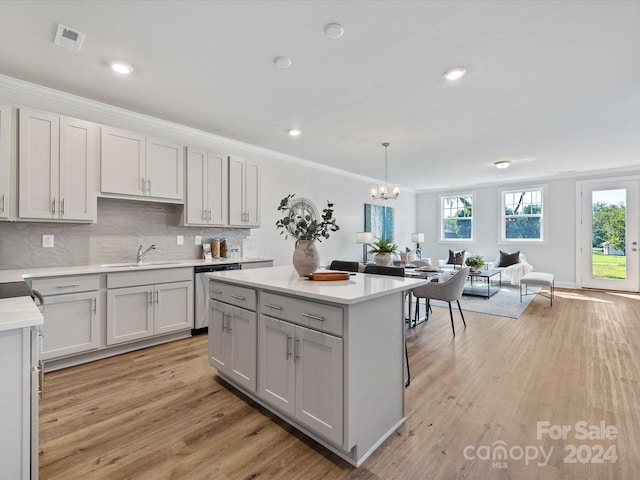 kitchen with stainless steel dishwasher, a healthy amount of sunlight, light hardwood / wood-style floors, and decorative light fixtures