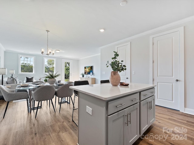 kitchen featuring pendant lighting, a kitchen island, gray cabinets, crown molding, and light hardwood / wood-style floors