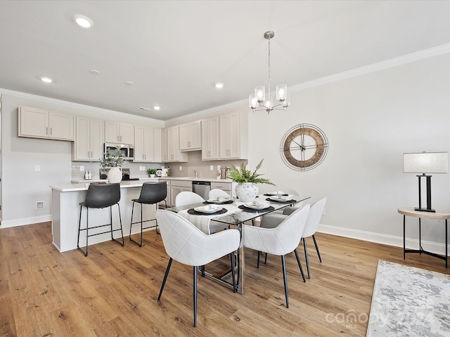 dining room featuring sink, crown molding, light hardwood / wood-style floors, and a chandelier