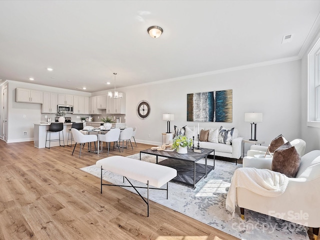 living room featuring crown molding, light hardwood / wood-style floors, and a chandelier