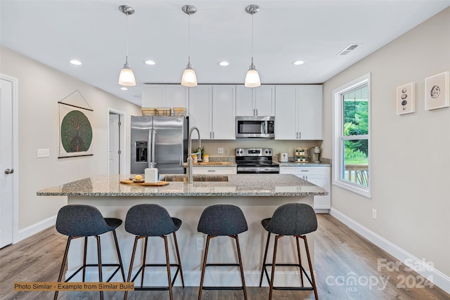 kitchen featuring light wood-type flooring, appliances with stainless steel finishes, and a kitchen island with sink