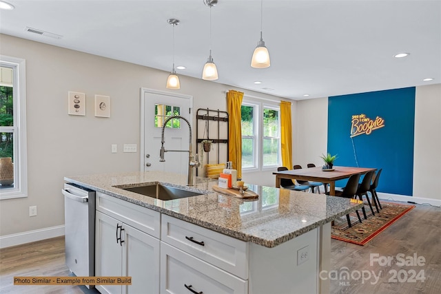 kitchen with white cabinets, dishwasher, light wood-type flooring, sink, and a kitchen island with sink