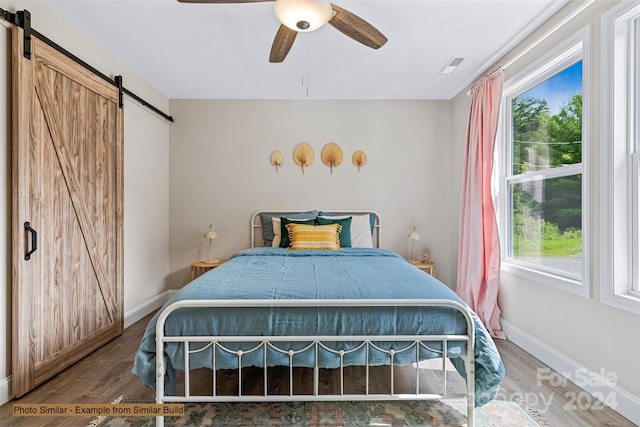 bedroom with hardwood / wood-style flooring, ceiling fan, and a barn door