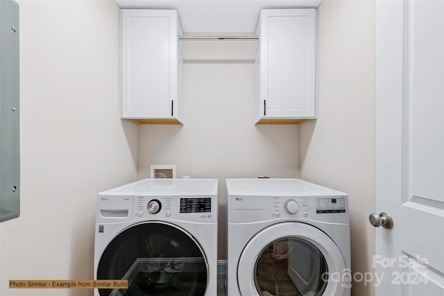 clothes washing area with cabinets and washing machine and dryer