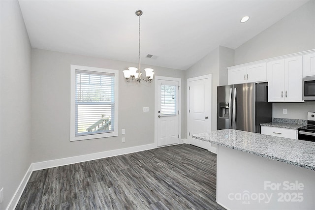 kitchen featuring lofted ceiling, hanging light fixtures, stainless steel appliances, light stone counters, and white cabinets